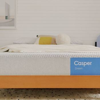 Casper's Dream mattress on a bed frame with pillows and a blanket folded on top.