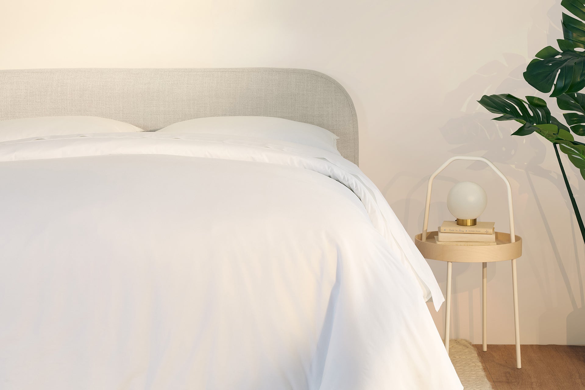 A fully made bed with a Drift Attachable Headboard, fog color. Close-up of right half.