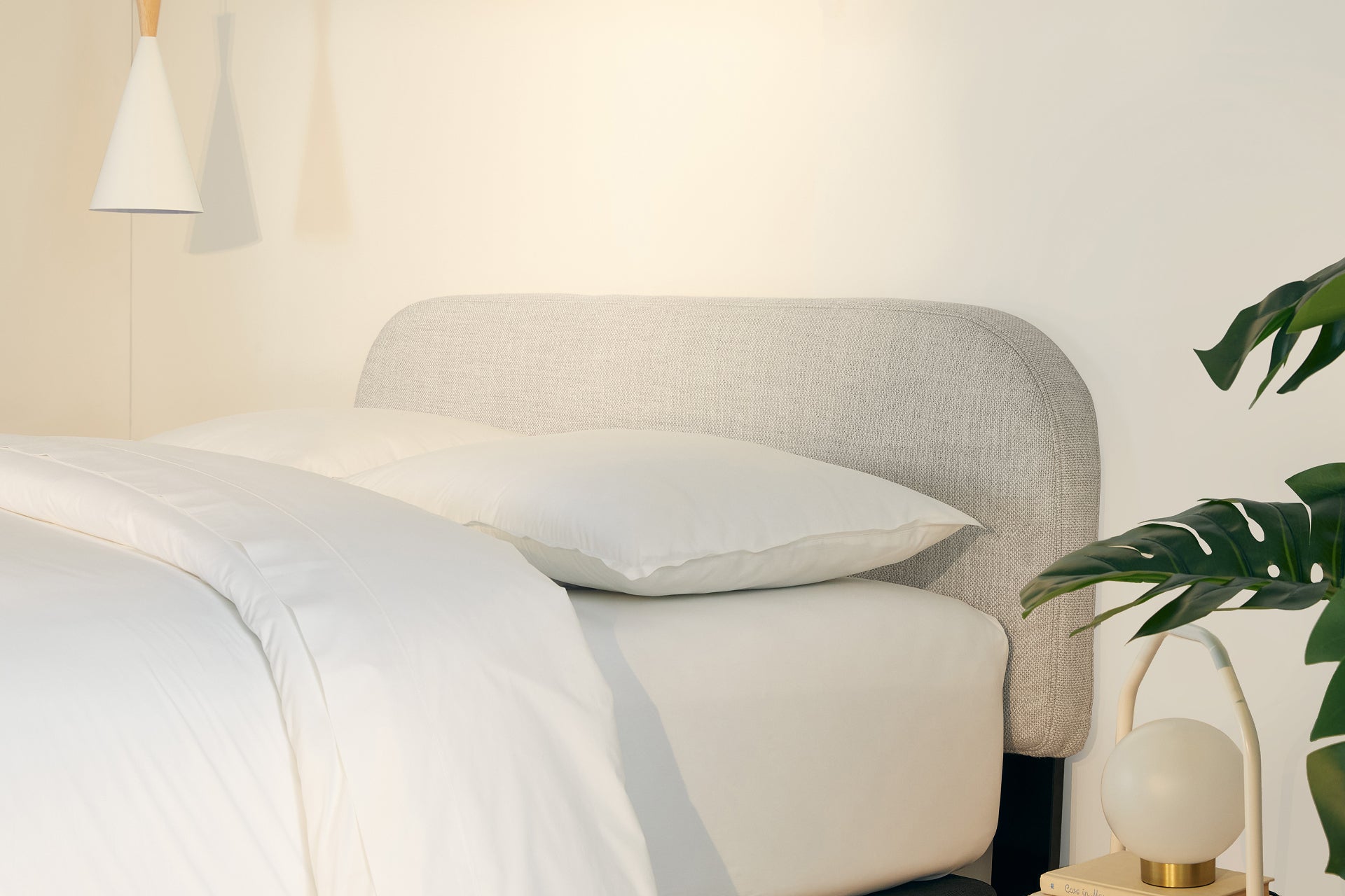 A fully made bed with a Drift Attachable Headboard, fog color. Side view.