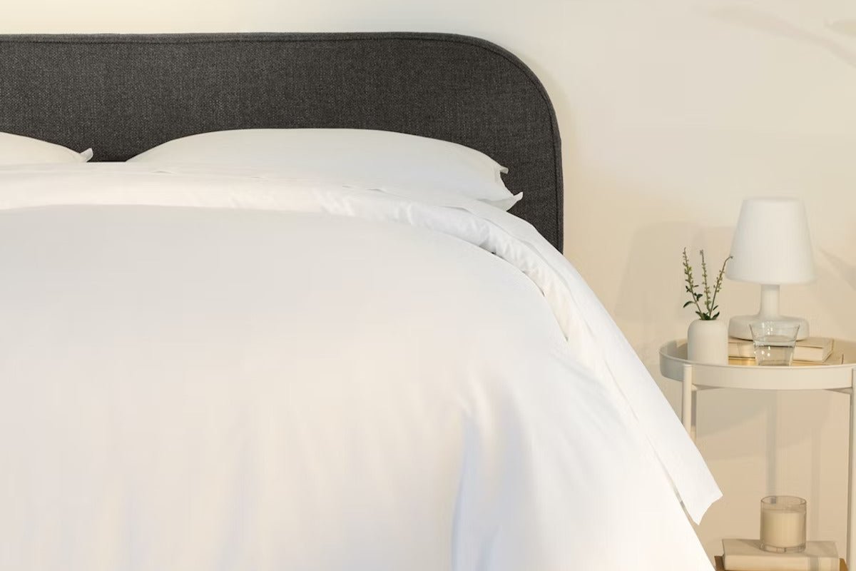 A fully made bed with a Drift Attachable Headboard, Slate color. Close-up of right half.