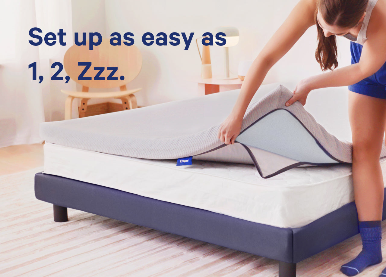 Set up as easy as 1, 2, Zzz. A person sets their new Essential Topper on top of their mattress with ease.