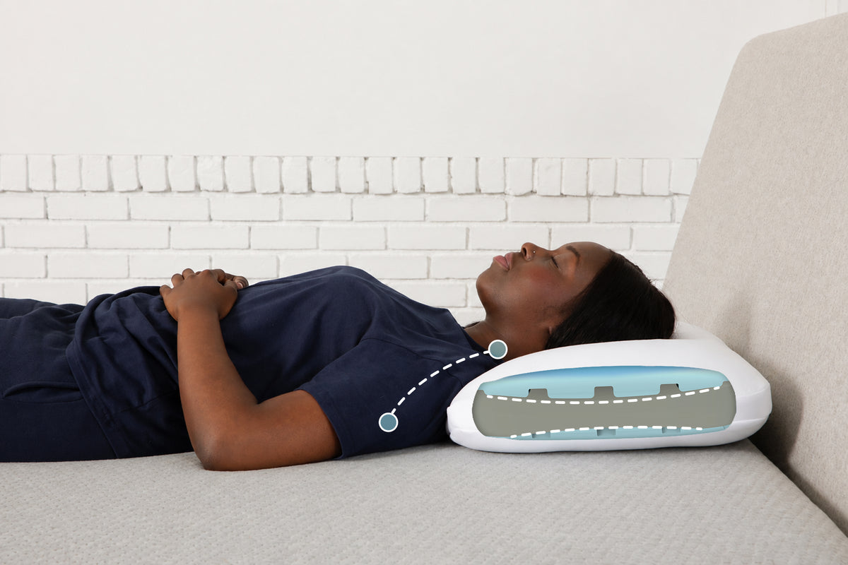 A woman lies in bed. The back of her head rests on Casper's Foam Snow Pillow. A graphic illustration on the pillow shows that it maintains optimal positioning for back sleepers.
