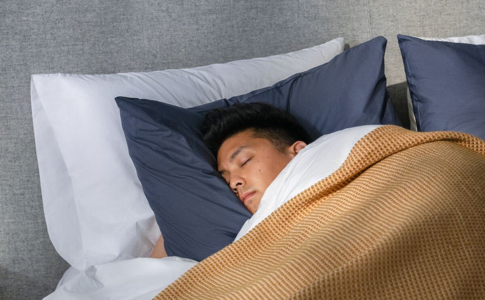 A person sleeps cozily on their side, resting their head on a Casper Foam Pillow with Snow Technology