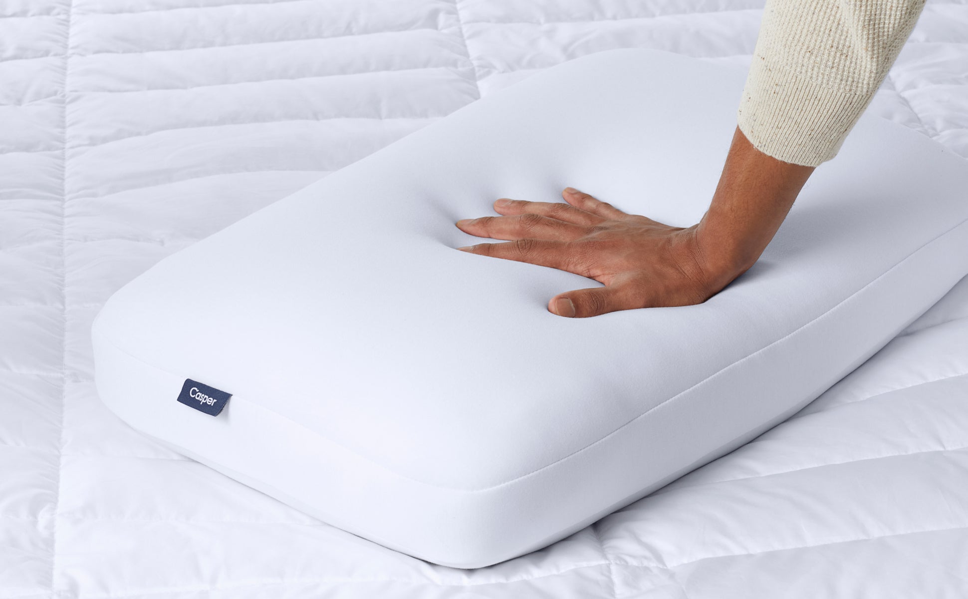 Close-up image of a person's hand pressing down on and feeling the firmness of the Foam Pillow.