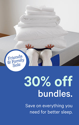 A person sits on the corner of a bed holding a stack of pillows, a mattress protector, and a sheet set. Text on the image reads "Friends and Family Sale. 30% off bundles. Save on everything you need for better sleep."