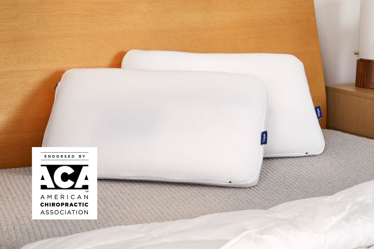 Casper's Hybrid Pillow Double Pack leaning against a wooden headboard. A badge on the image says "Endorsed by the ACA - American Chiropractic Association"