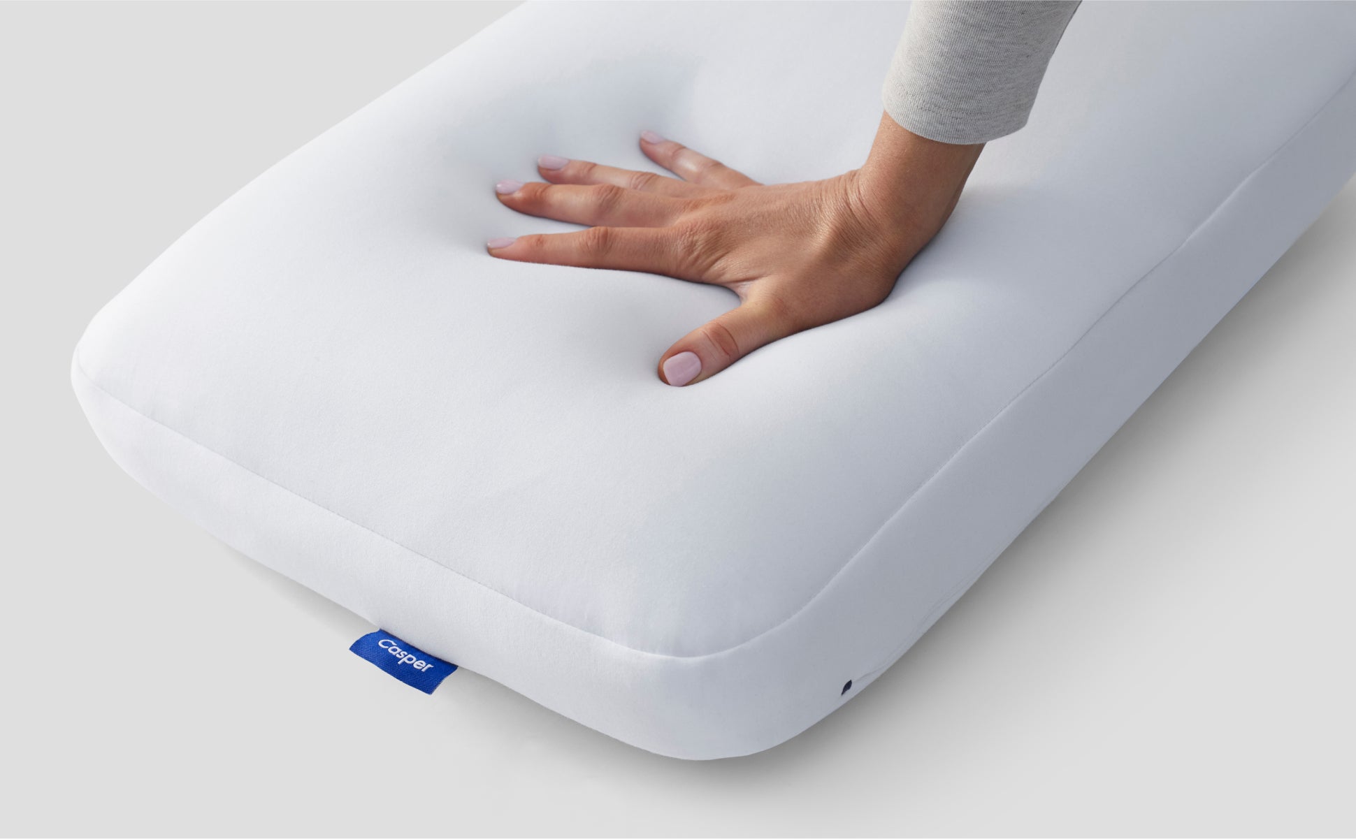 A hand feeling the Casper Hybrid Pillow