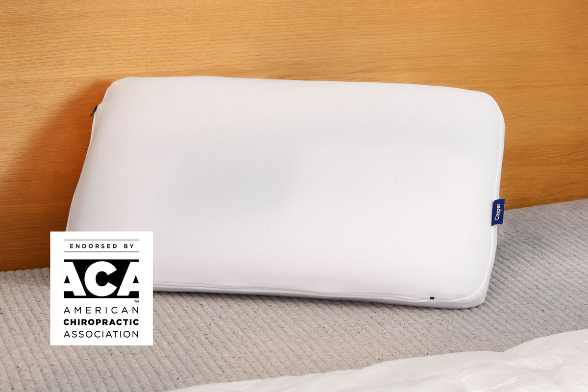Casper's Hybrid Pillow leaning against a wooden headboard. A badge on the image says "Endorsed by the ACA - American Chiropractic Association"