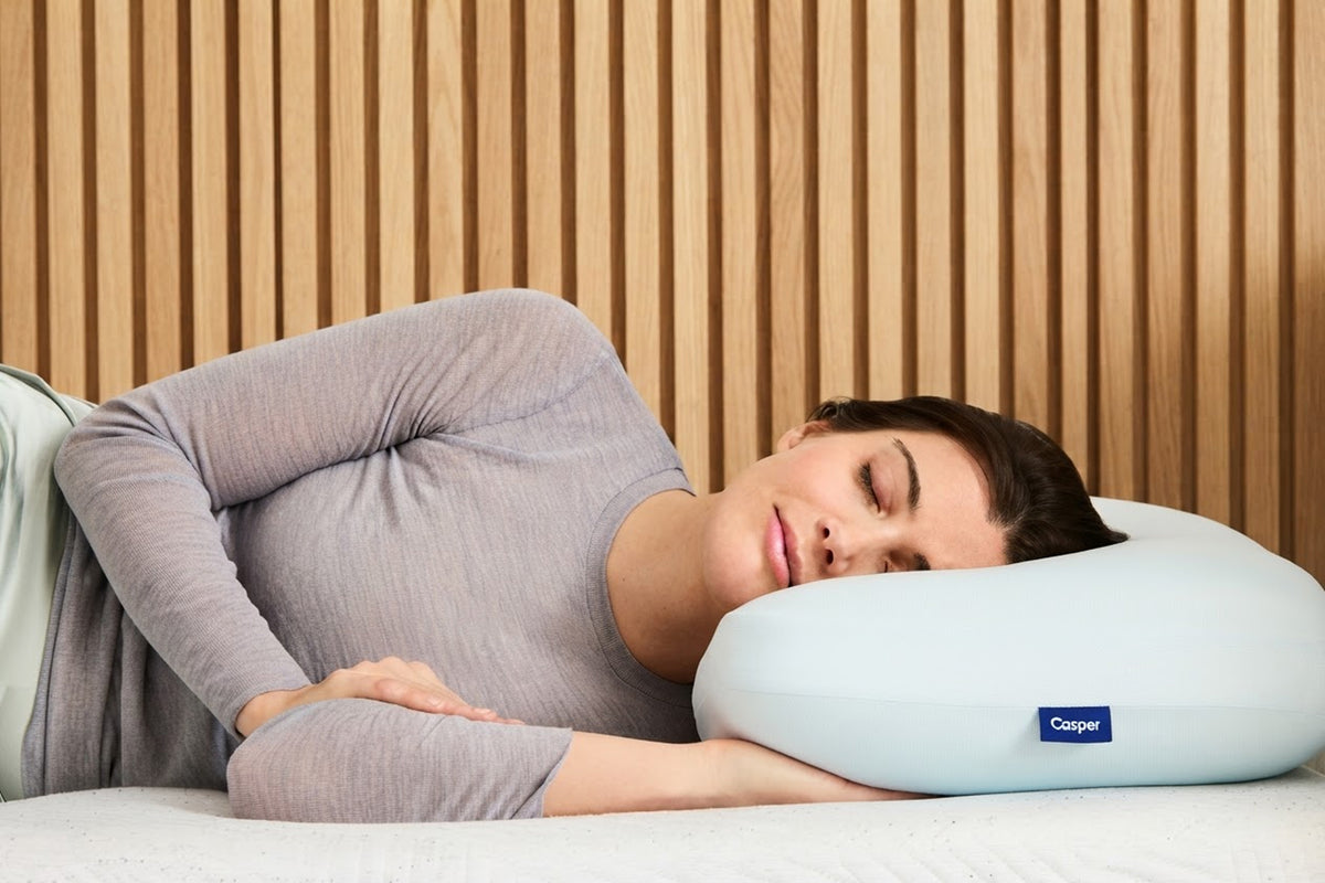 A woman lies on her side on a Casper Hybrid Snow Pillow.