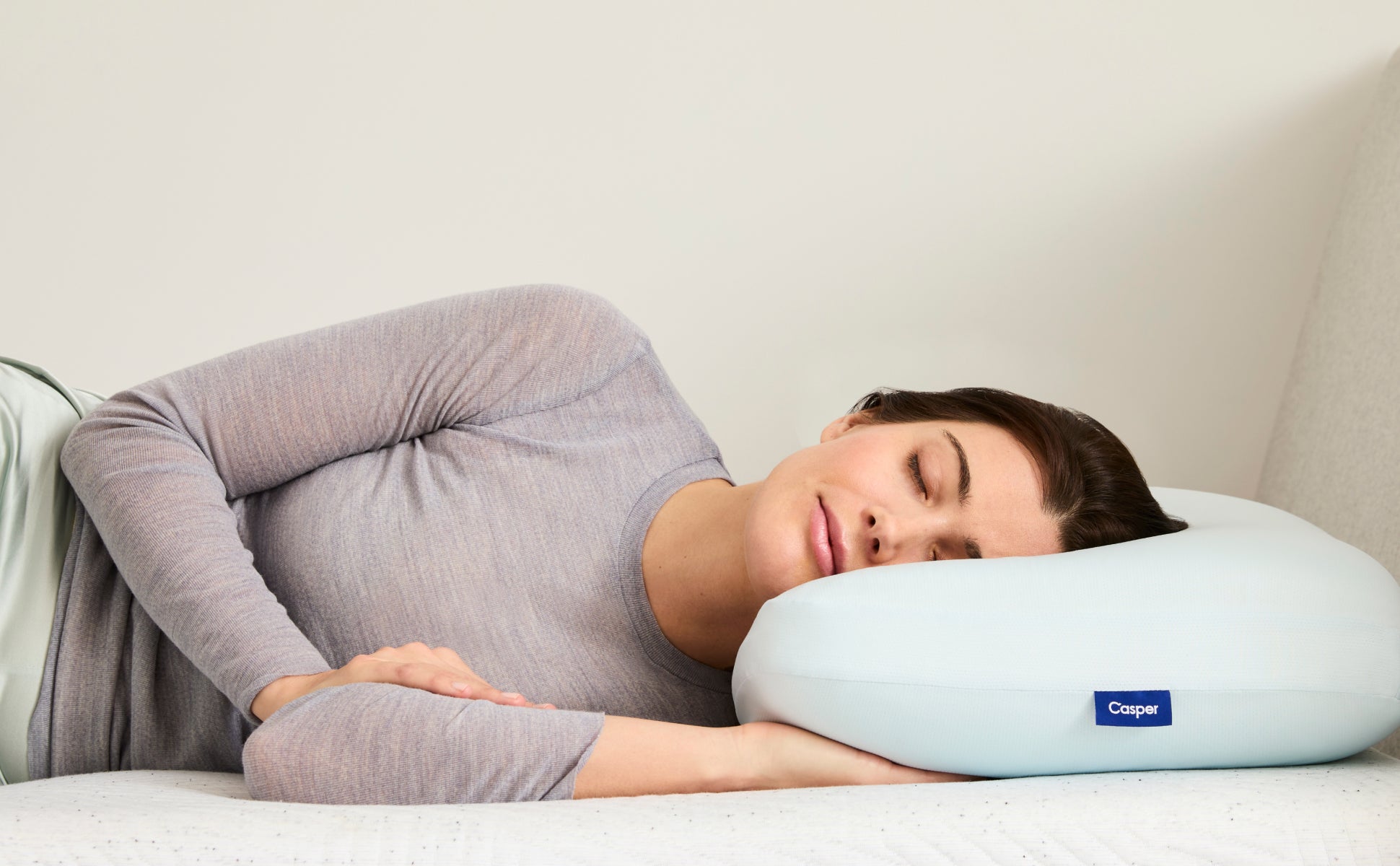 A person lies on their side, resting their head on the Hybrid Pillow with Snow Technology.