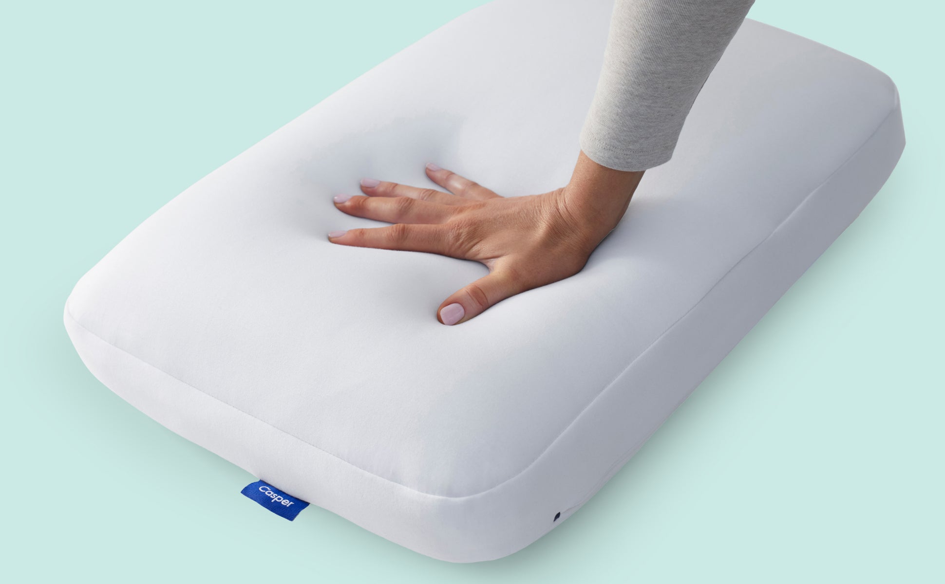 A person's hand pressing down and feeling the firmness of the Hybrid Pillow.