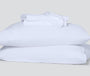 Folded pillowcases and a hyperlite sheet set, white, sitting atop two pillows