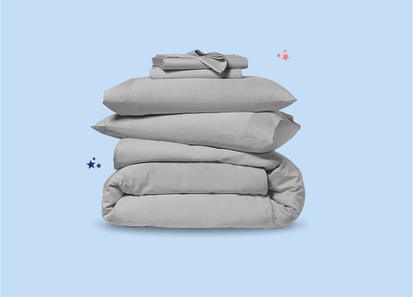 Folded pillowcases and sheet sets stacked on top of a folded duvet.