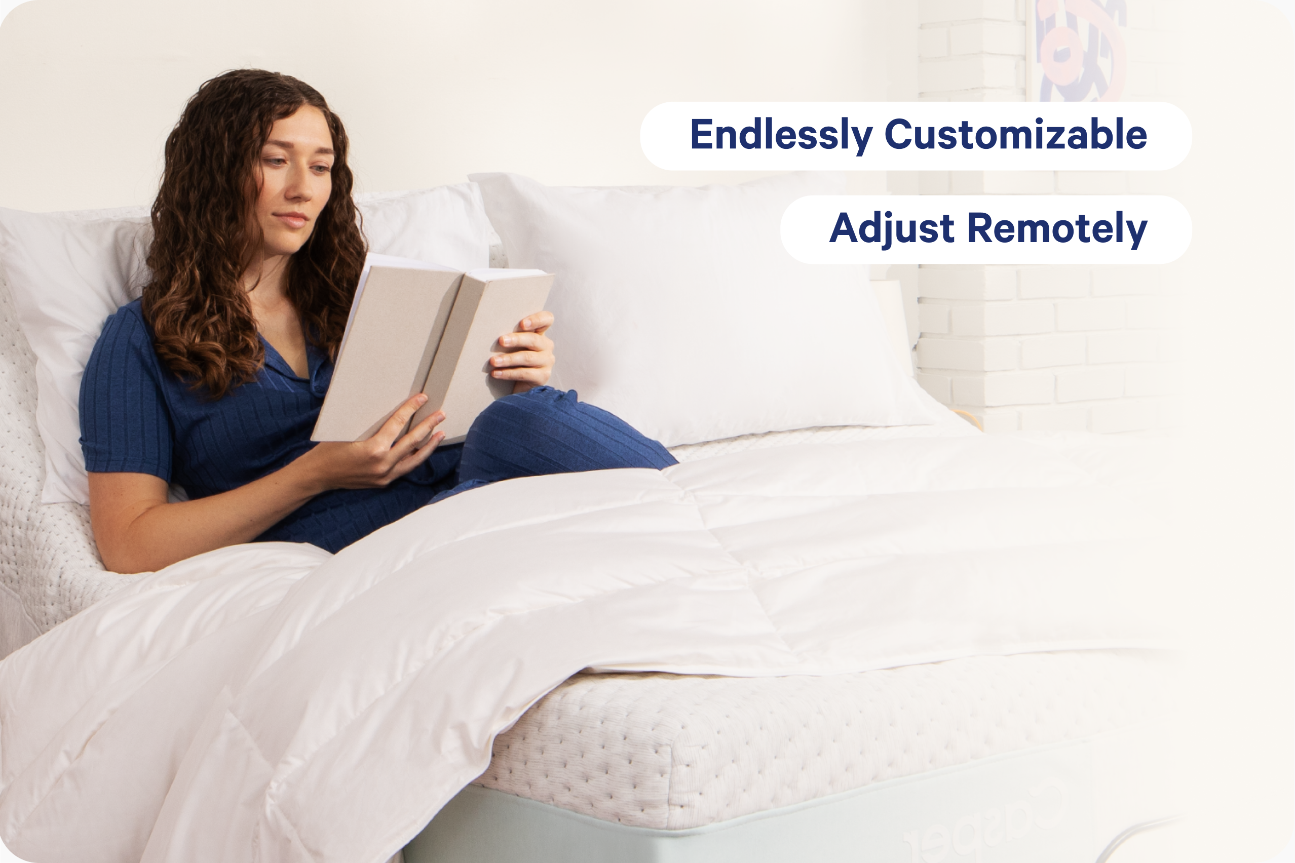 A woman in a blue ribbed short-sleeve top and matching pants sits in bed reading a book, with white bedding and pillows around her. Two text callouts on the right read 'Endlessly Customizable' and 'Adjust Remotely," referring to the adjustable bed frame.