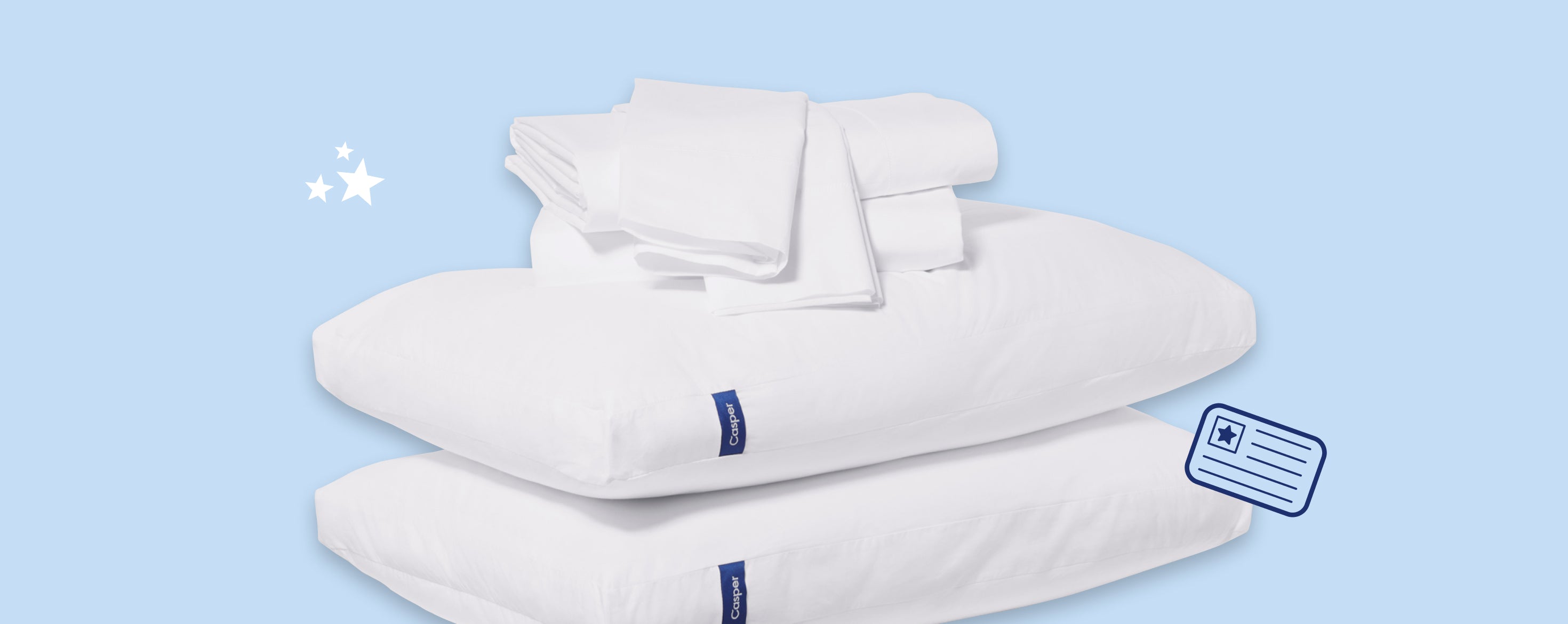 Folded pillowcases and sheet sets stacked in top of two Casper pillows against a light blue background