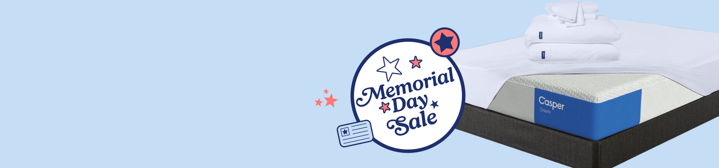 Folded pillowcases and sheet sets re stacked on top of two pillows on a mattress protector over a Casper Dream mattress, set on top of a bed frame. A computer generated badge appears next to the image which says Memorial Day Sale.