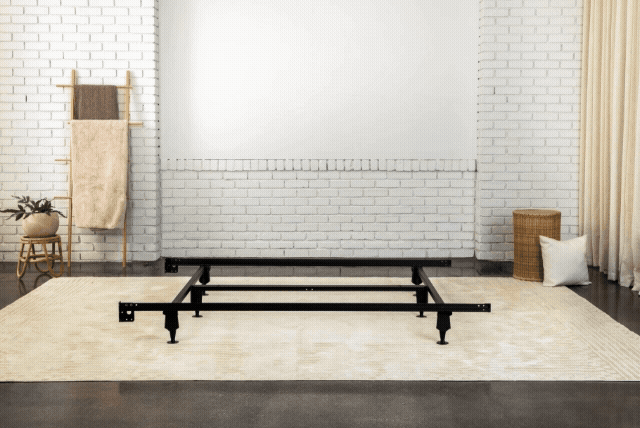 GIF of a metal bed frame being topped with a foundation and a mattress