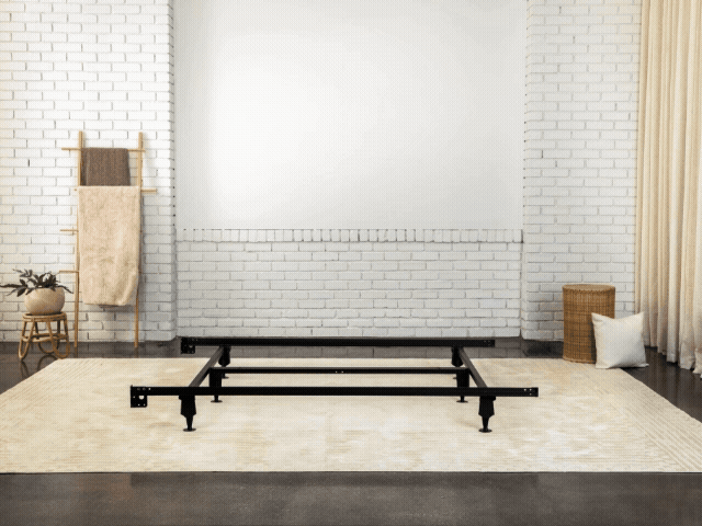 GIF of a metal bed frame being topped with a foundation and a mattress
