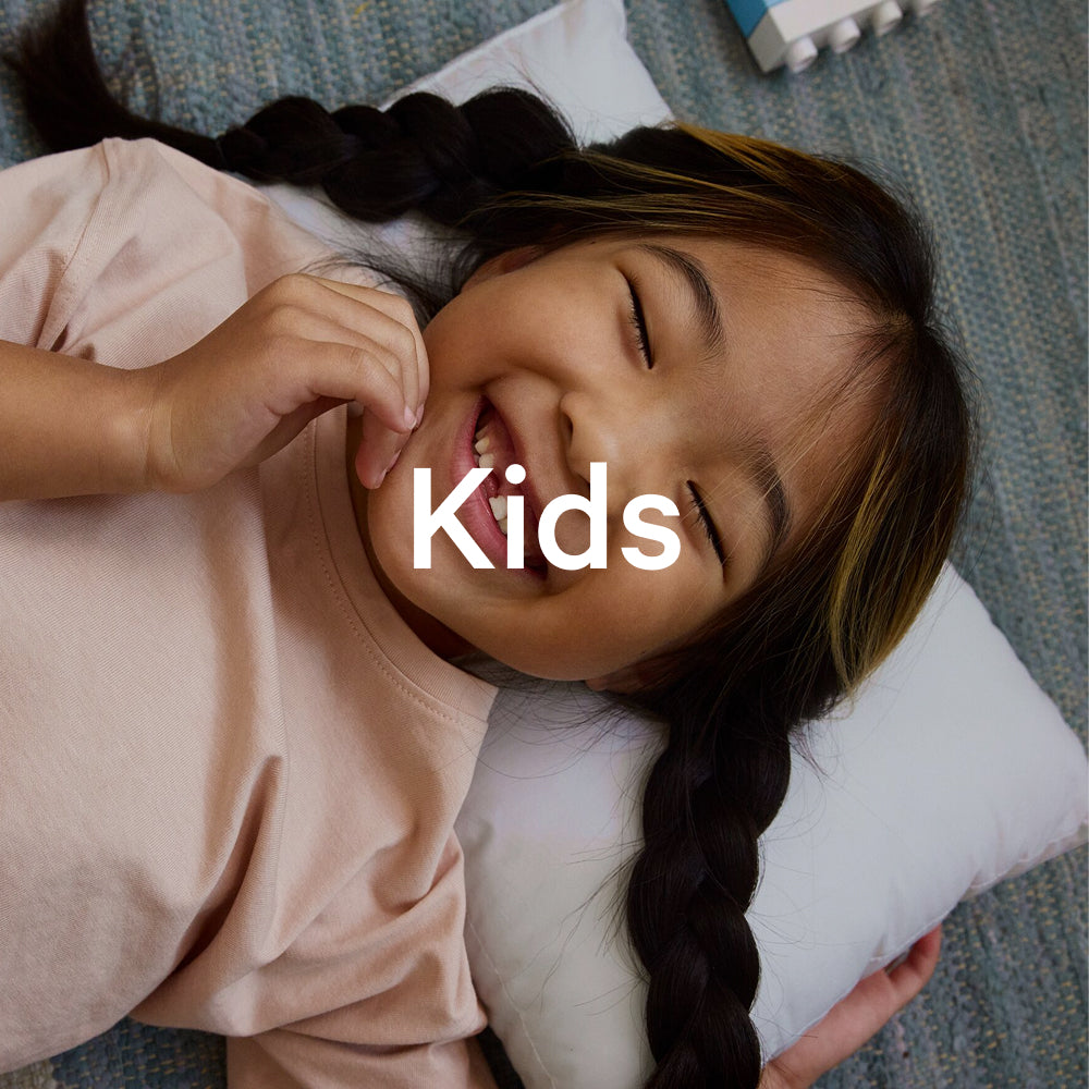 The word "kids" appears on an image of a little girl smiling while she lies on the Nap Pillow.