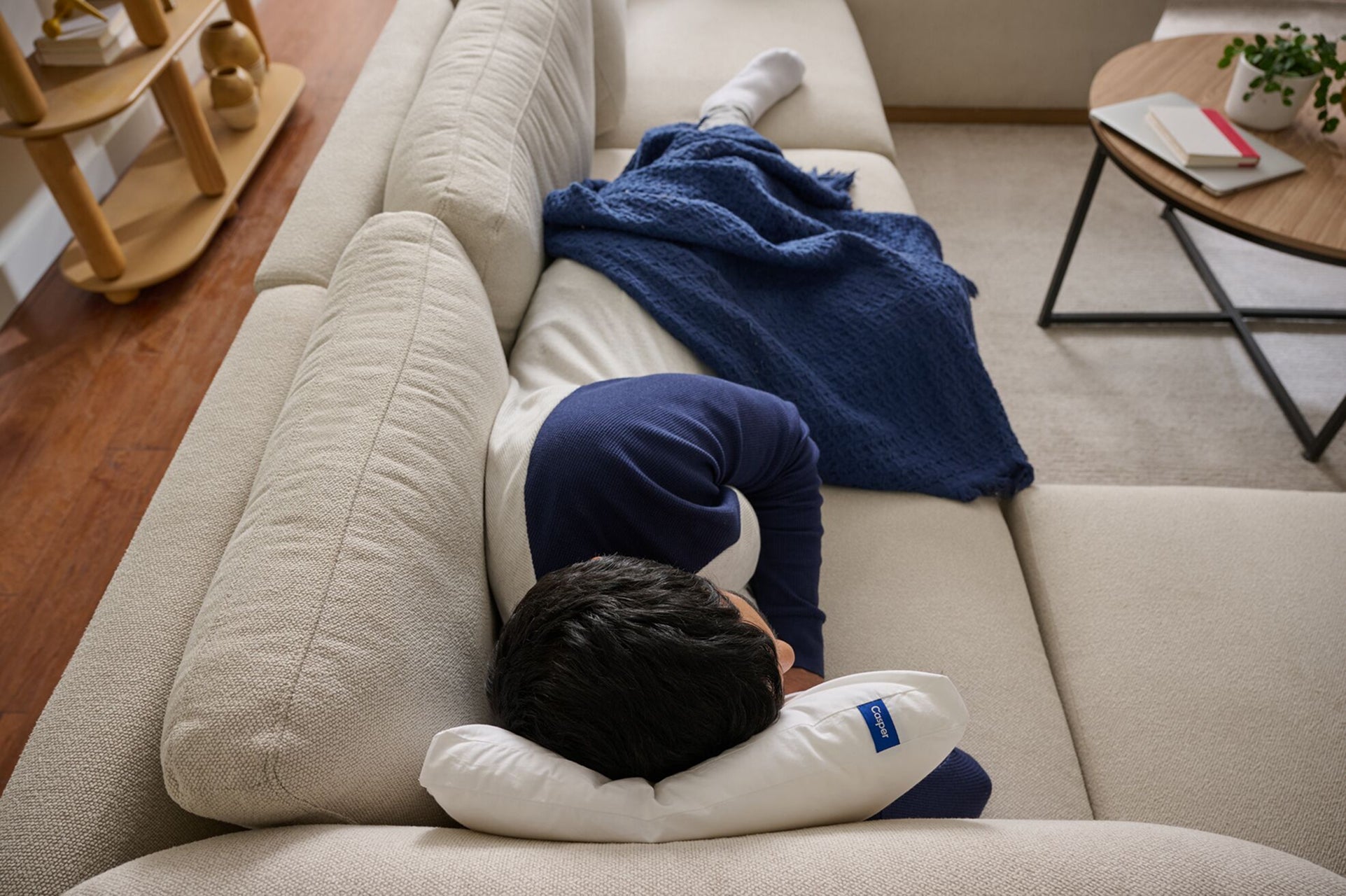 Overhead view of a person taking a nap on a couch with their Casper Nap Pillow.