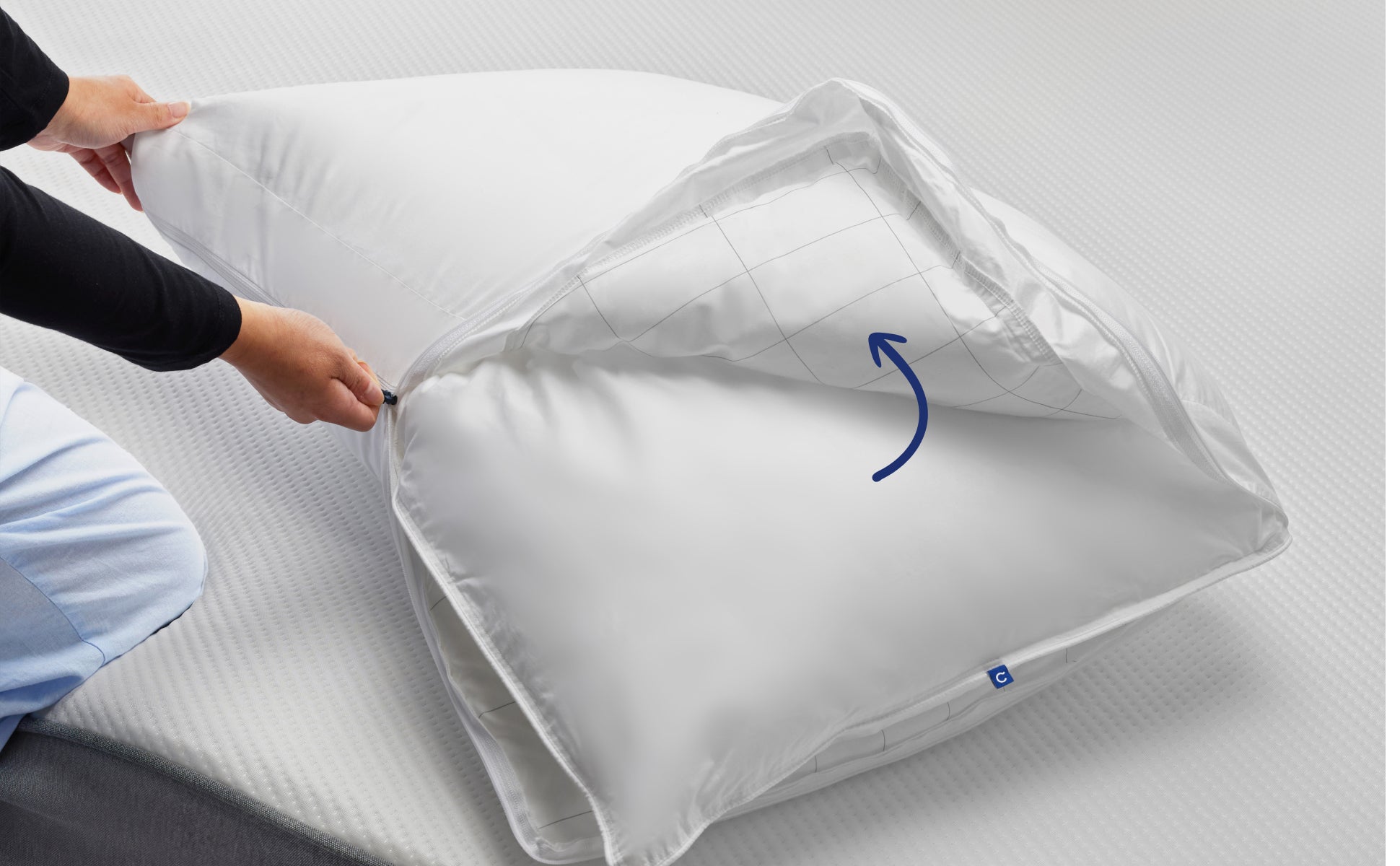 A person's hands unzipping the Casper Original Pillow to show that this product is one pillow inside another pillow.