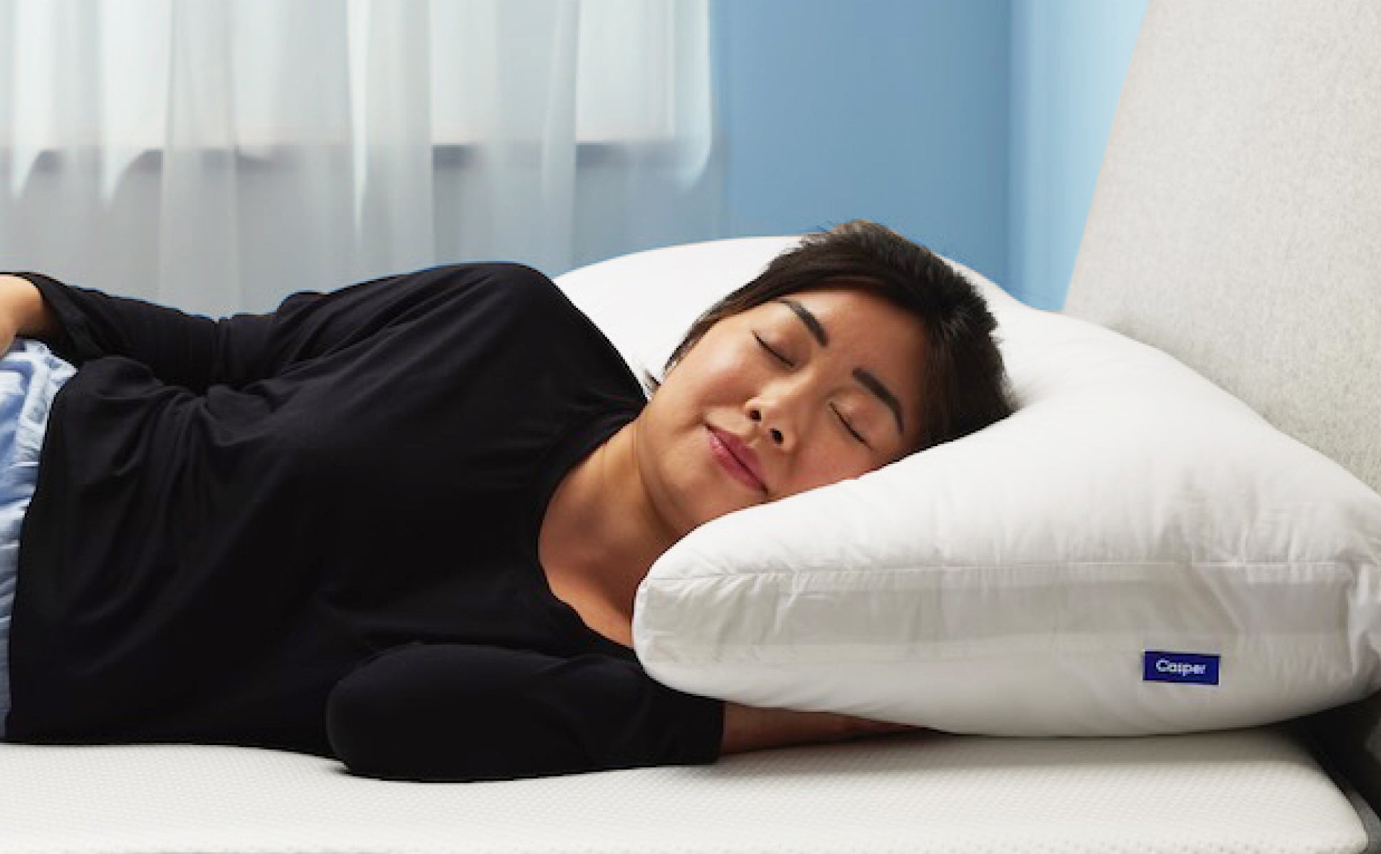 A person lying on their side on a Casper Original Pillow with a smile on their face.
