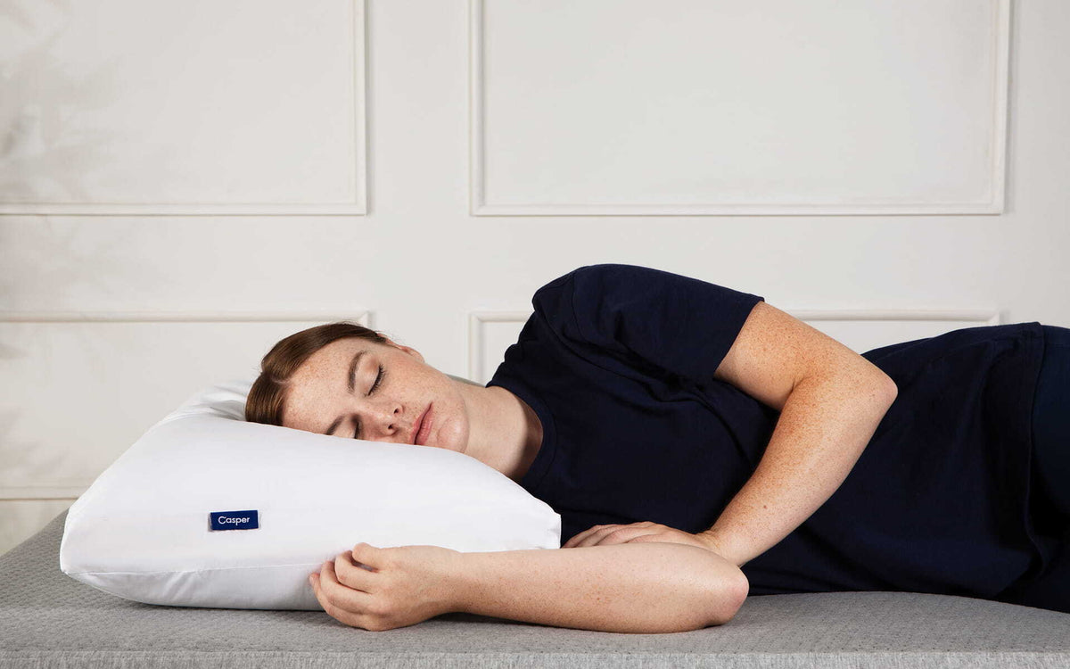 A woman sleeps on her side in bed.