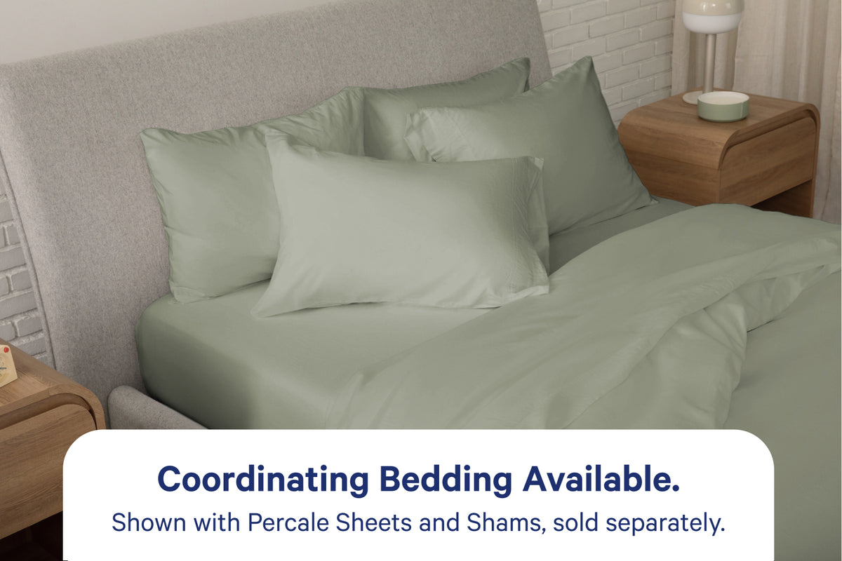 A fully dressed bed with eucalyptus-green bedding. An overlay on the image with text reads 'Coordinating Bedding Available. Shown with Percale Sheets and Shams, sold separately.'