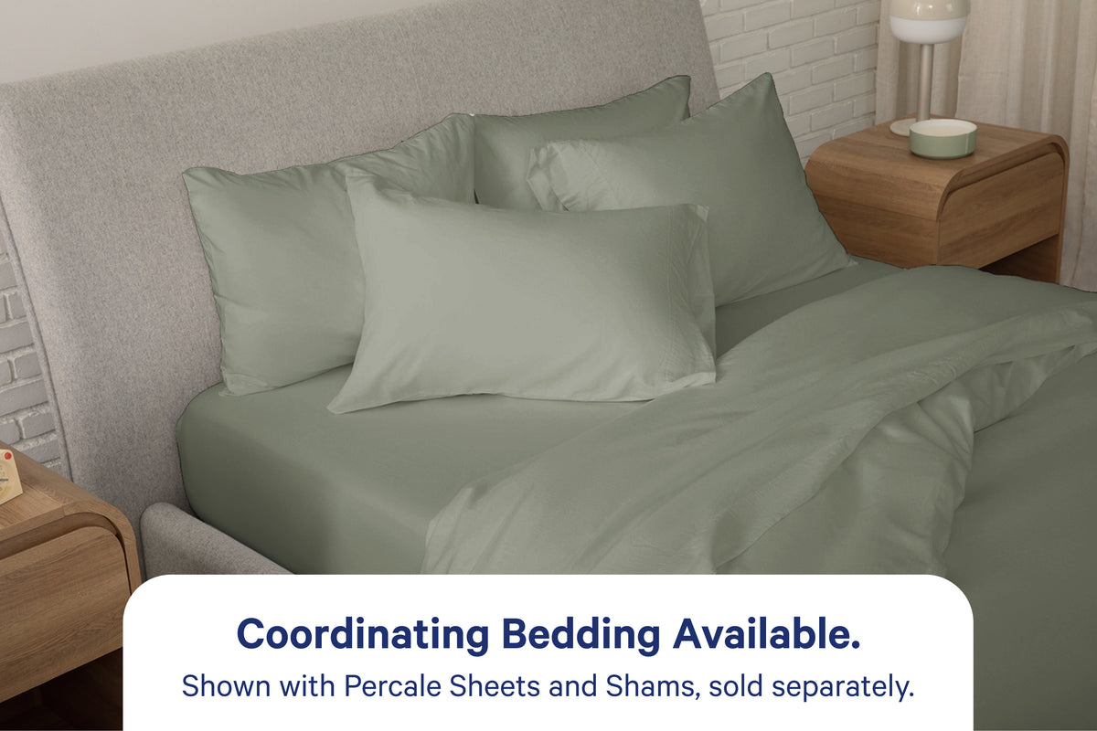 A fully dressed bed with eucalyptus-green bedding. An overlay on the image with text reads 'Coordinating Bedding Available. Shown with Percale Sheets and Shams, sold separately.'