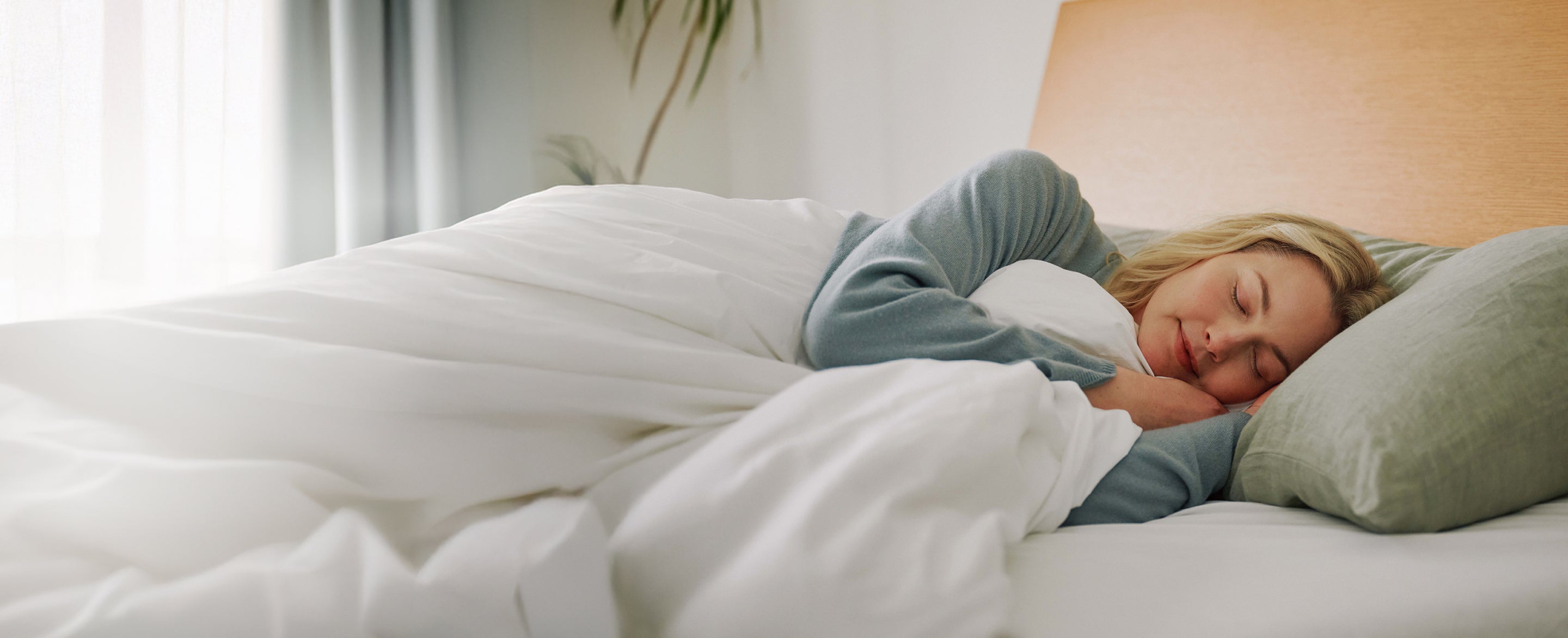 A woman sleeps cozily on her side in bed.