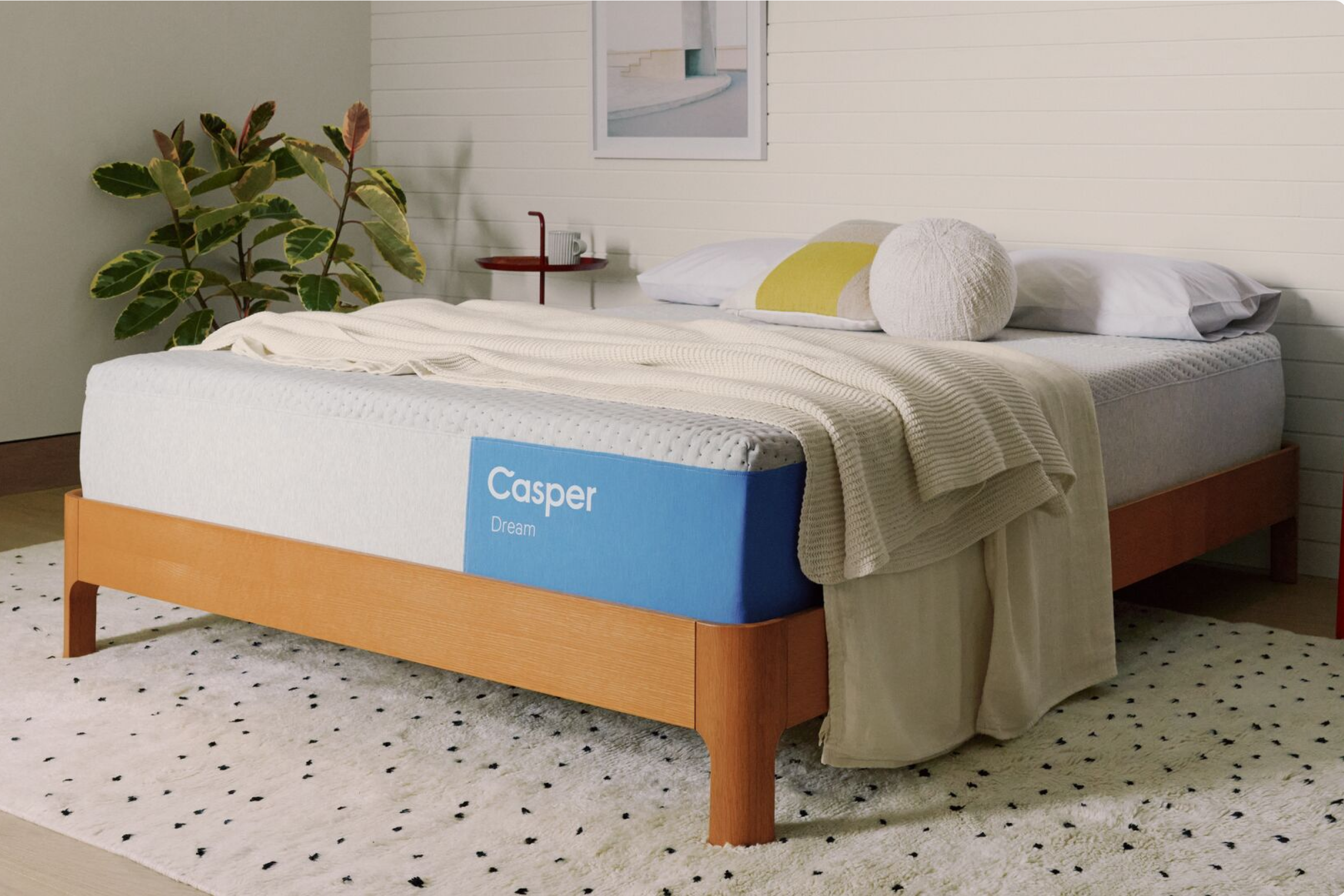 A wooden bed frame with a Casper Dream mattress shown in a styled bedroom setting.