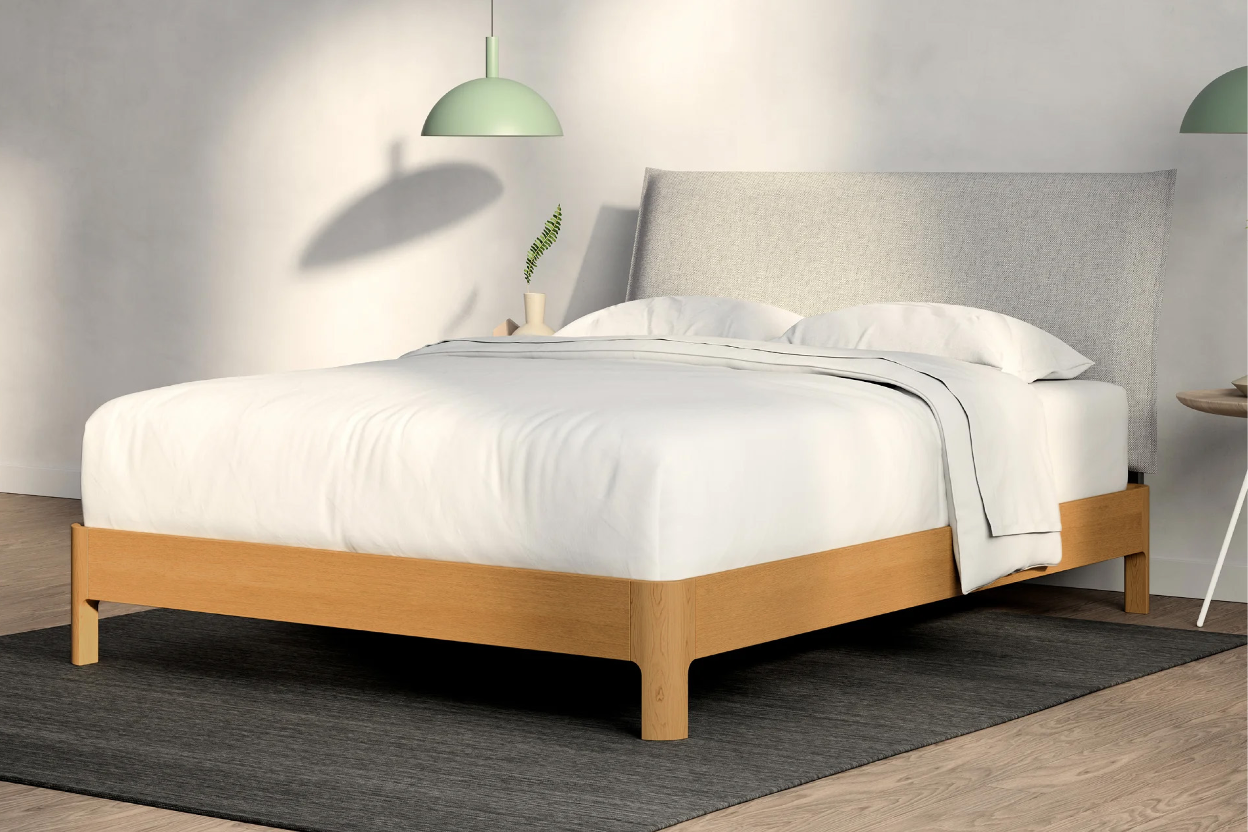 Corner view of a mattress on a wooden bed frame with a Pillow Repose Headboard, light gray color in a modern bedroom setting