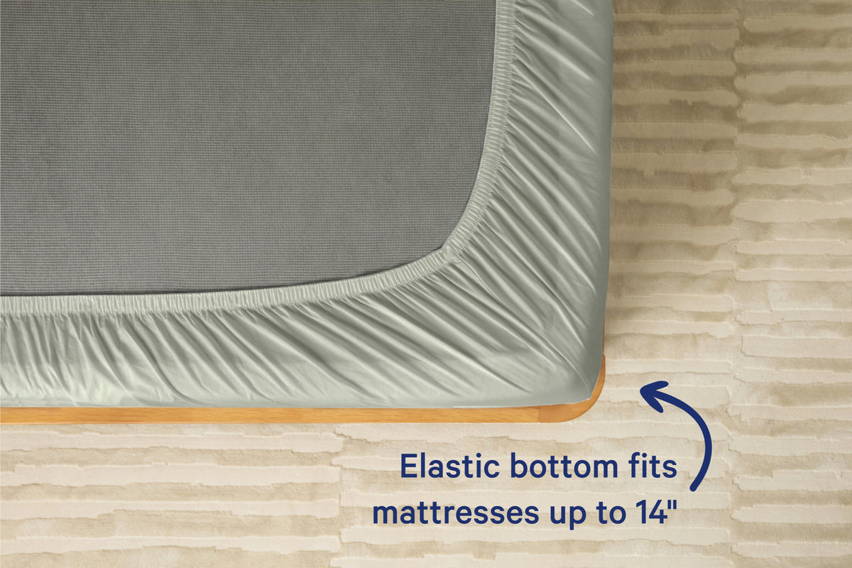 Underside view of a mattress with a eucalyptus-green colored fitted sheet. Text on the image reads 'Elastic bottom fits mattresses up to 14 inches.'