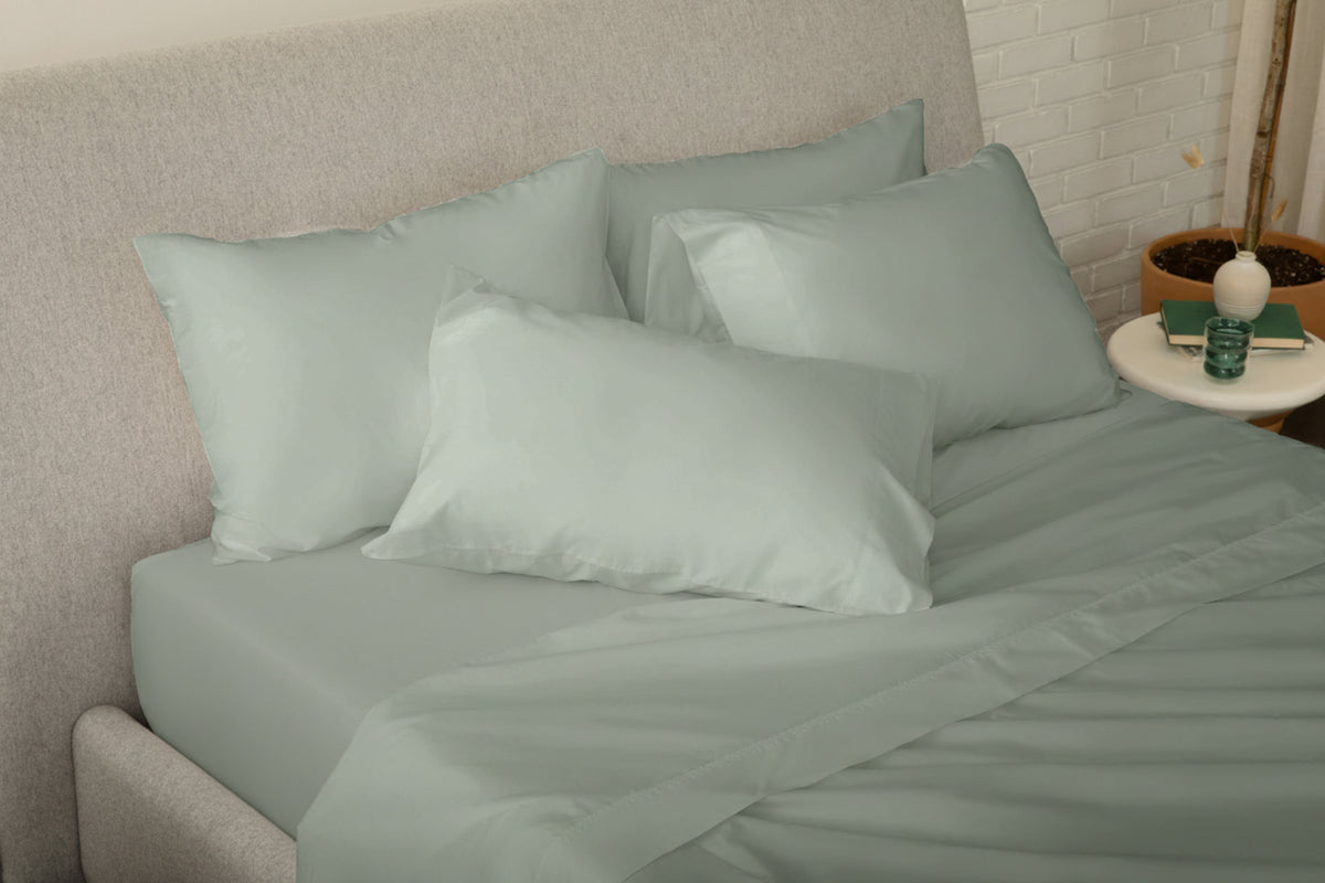 Fully dressed bed with eucalyptus-green bedding