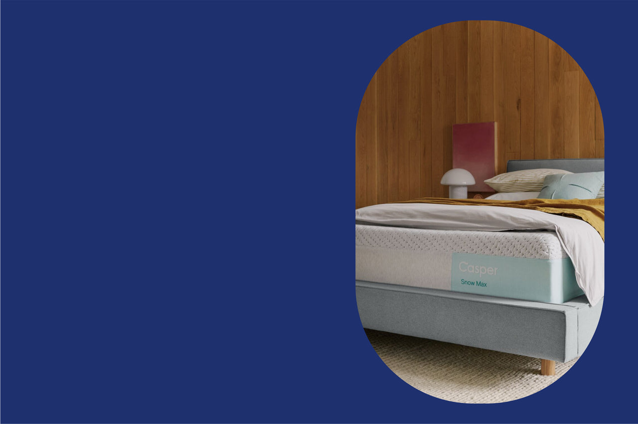Casper's Snow Max mattress on a bed frame with a blanket and pillows on top. 