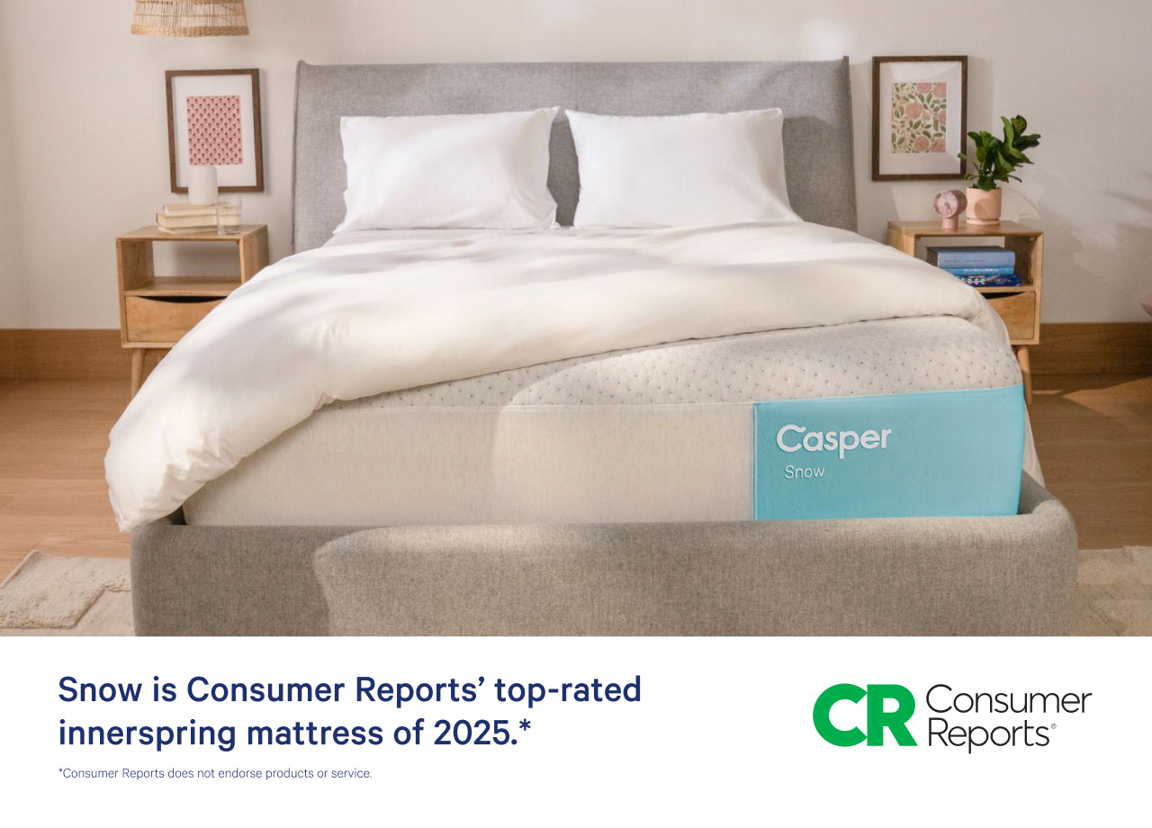 Front-facing image of the Casper Snow mattress on a bed frame with two pillows and a blanket folded on top. Beneath he image it says "Snow is Consumer Reports' top-rated innerspring mattress of 2025." Consumer Reports does not endorse products or service.