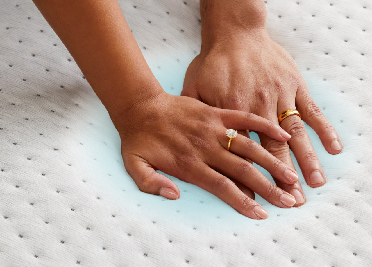 Two people's hands push down on the Snow Max mattress to feel its coolness.