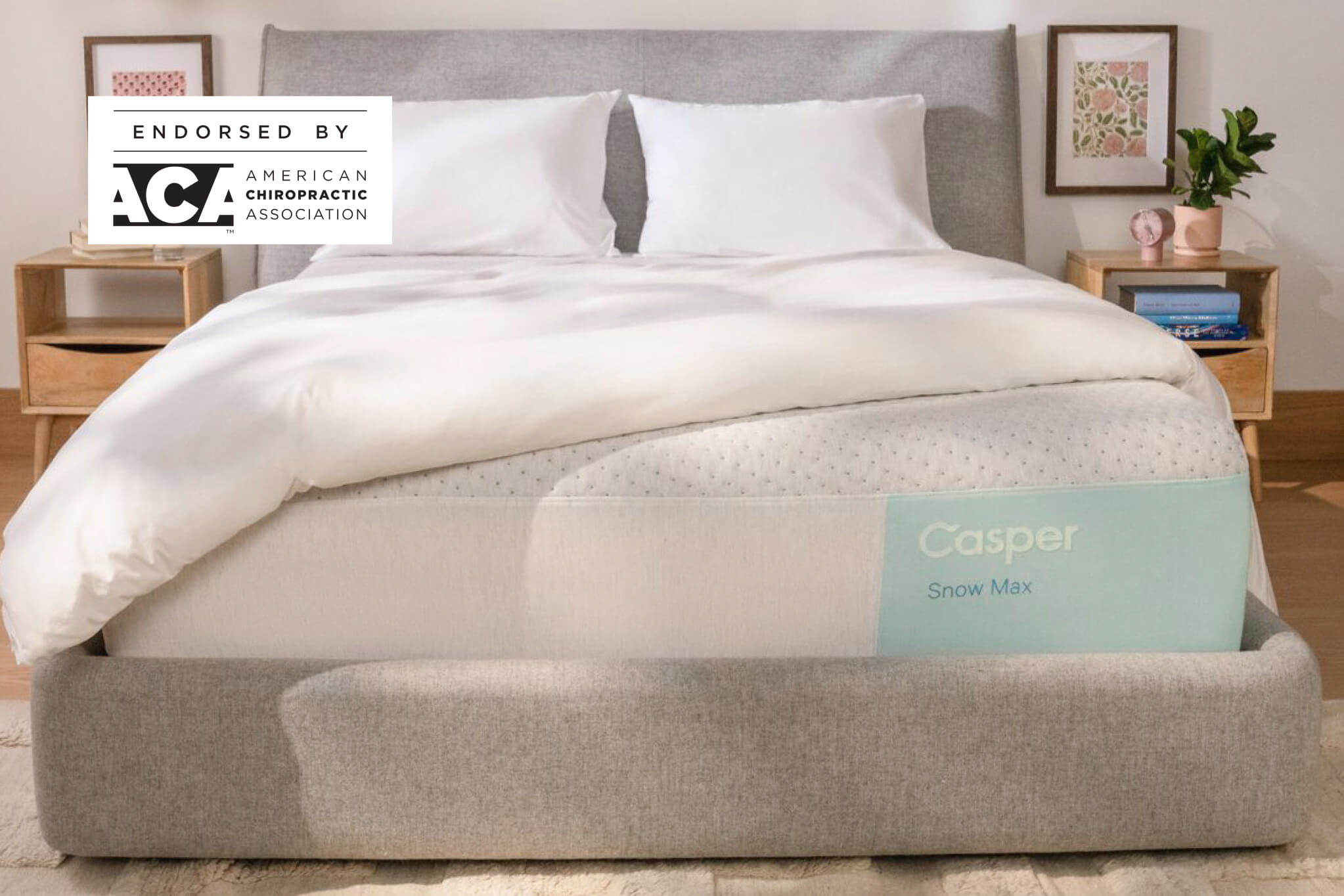 Front-view of the Casper Snow Max mattress in a bed frame with two pillows and a blanket folded on top. In the top-left corner of the image appears a badge which says, "Endorsed by ACA the American Chiropractic Association."