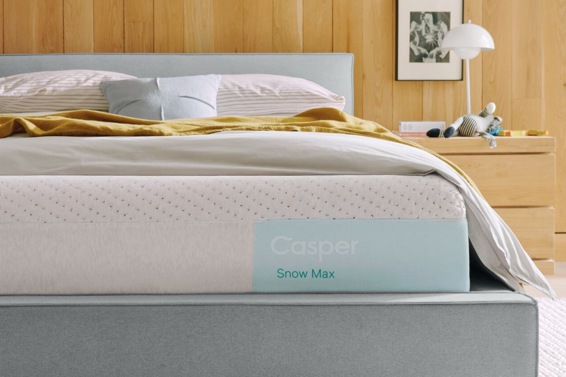 Casper's Snow Max mattress on a bed frame with pillows and a blanket