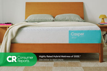 Front-view of the Casper Snow mattress in a bed frame with two pillows and a blanket folded on top. Beneath the image appears text which reads "Consumer Reports. Highly rated hybrid mattress of 2025.* See below to learn more. Consumer Reports does not endorse products or service."