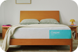 Casper's Snow mattress on a bed frame with pillows and a blanket folded on top.