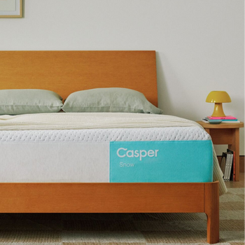 Casper's Snow mattress on a bed frame with pillows and a blanket folded on top.