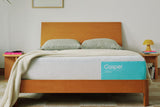 Casper's Snow mattress on a bed frame with pillows and a blanket folded on top.