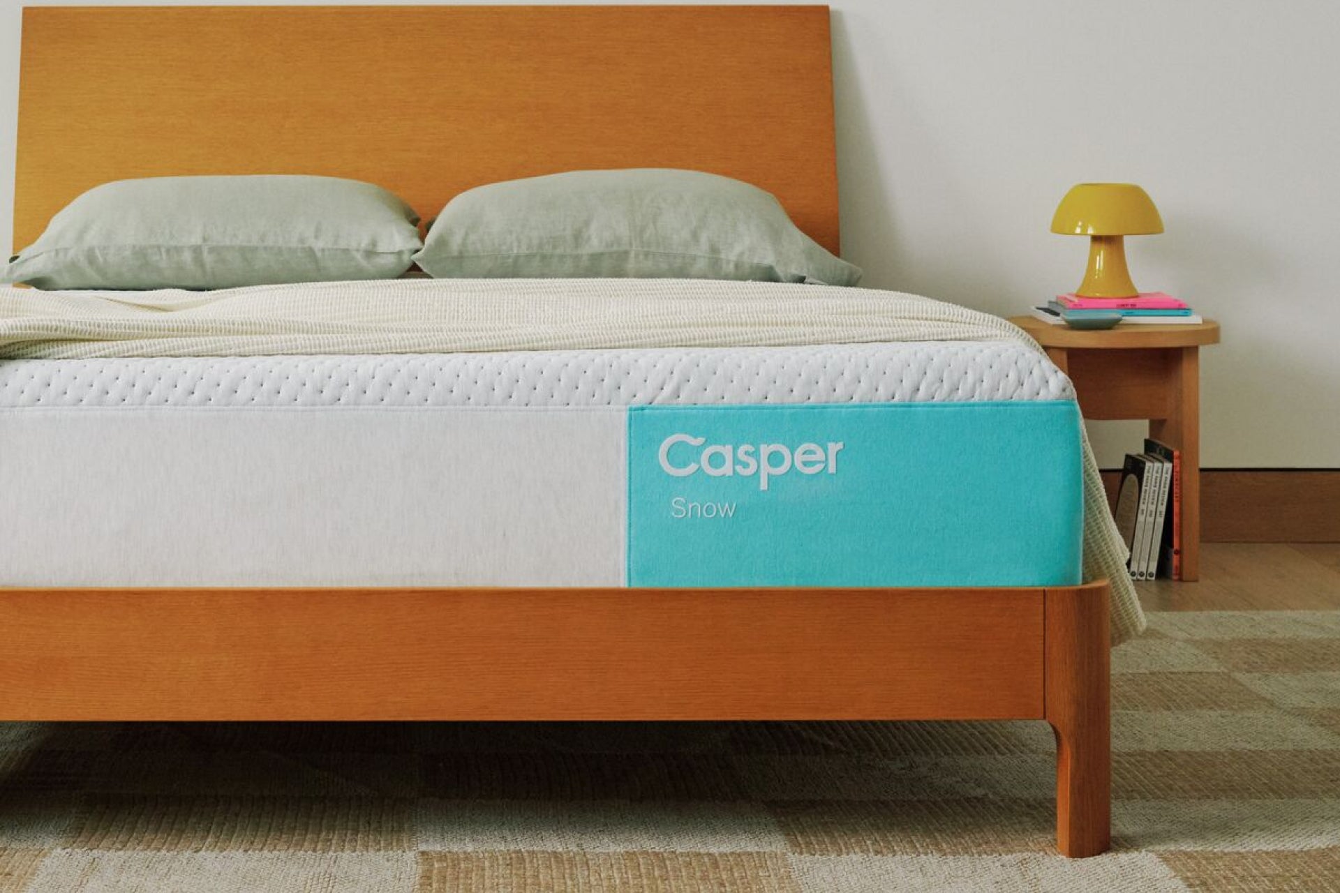 Casper's Snow mattress on a wooden bed frame with pillows and a blanket