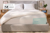 Front-view of the Casper Snow Max mattress in a bed frame with two pillows and a blanket folded on top. In the top-left corner of the image appears a badge which says, "Endorsed by ACA the American Chiropractic Association."