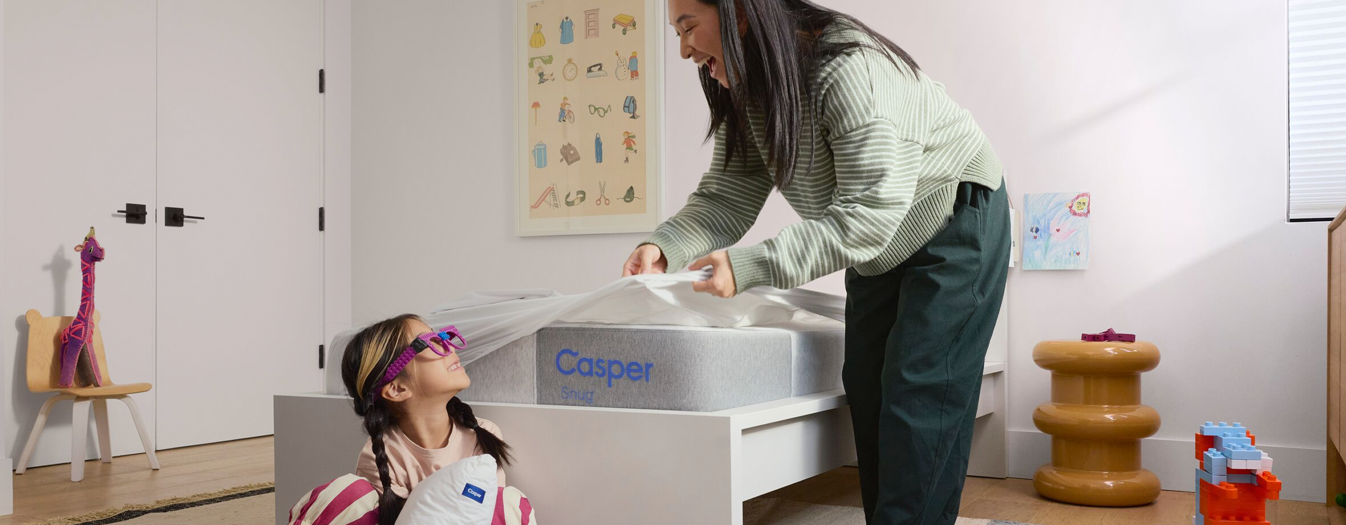 A mother and her child in a bedroom setting with a Casper Snug™ mattress