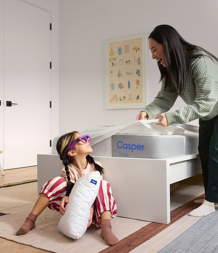 A mother and her child in a bedroom setting with a Casper Snug™ mattress