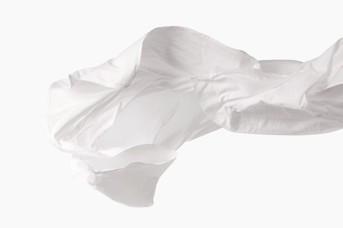 A still shot of a white bed sheet being tossed in the air against a white background