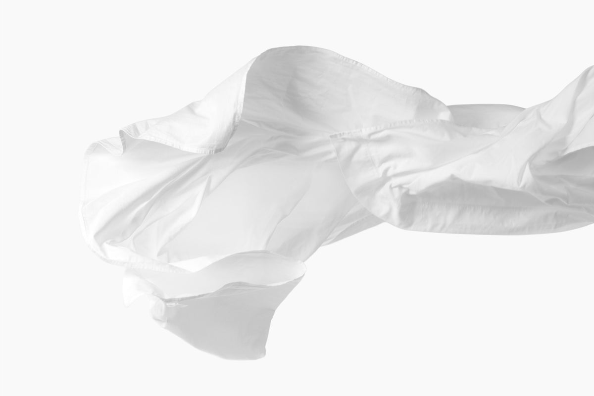 A still shot of a white bed sheet being tossed in the air against a white background