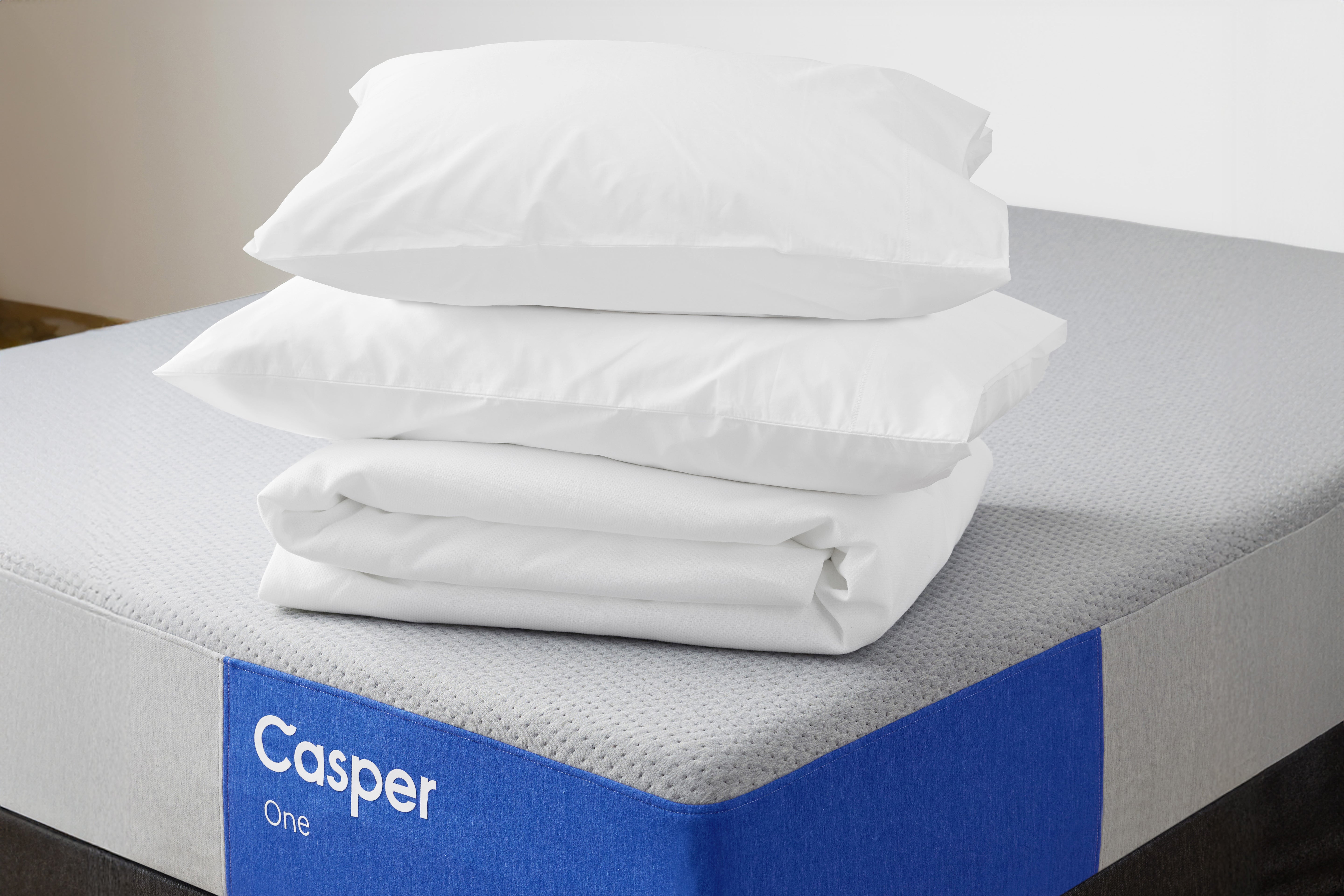 The One mattress with a folded mattress protector and two pillows on top